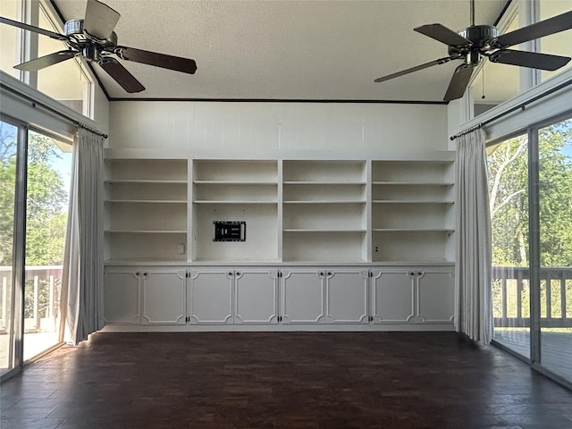 unfurnished living room with lofted ceiling, a ceiling fan, built in features, and dark wood-type flooring
