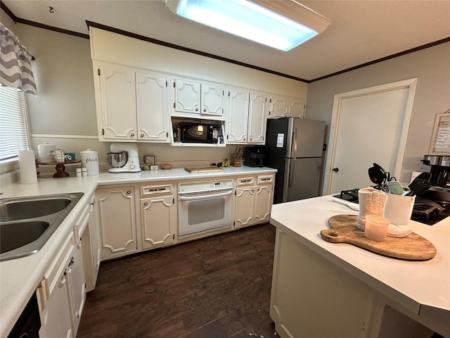 kitchen featuring a sink, white oven, black microwave, ornamental molding, and freestanding refrigerator