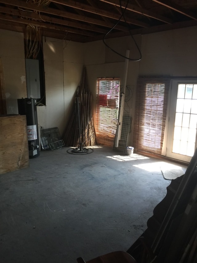 interior space featuring unfinished concrete floors, water heater, electric panel, and plenty of natural light