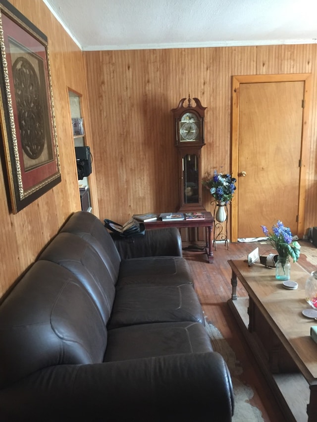 living room with wood finished floors, wood walls, and ornamental molding