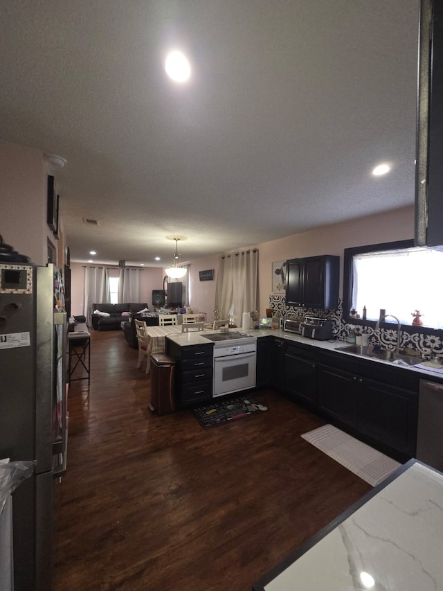 kitchen featuring dark wood-style floors, light countertops, a sink, a peninsula, and open floor plan