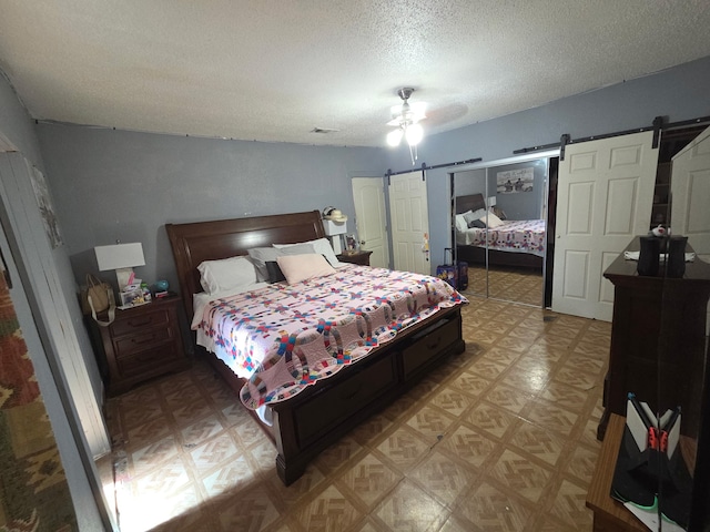 bedroom featuring a barn door, light floors, visible vents, a textured ceiling, and ceiling fan