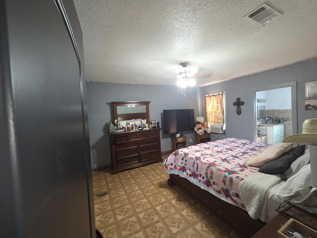 bedroom with light floors, a ceiling fan, visible vents, and a textured ceiling
