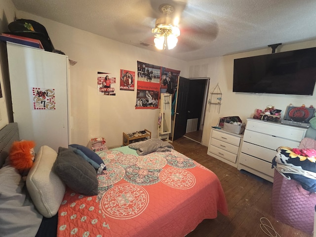 bedroom featuring dark wood finished floors, a ceiling fan, a textured ceiling, and visible vents