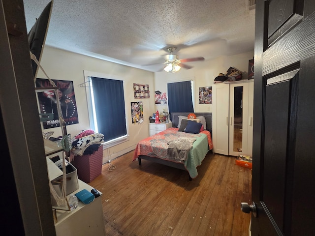 bedroom with a ceiling fan, hardwood / wood-style floors, and a textured ceiling