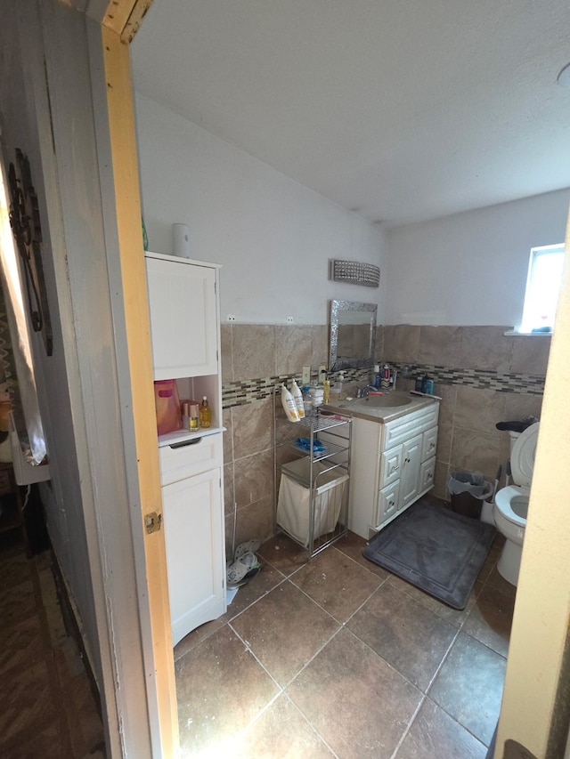 bathroom with tile walls, wainscoting, a sink, and tile patterned flooring