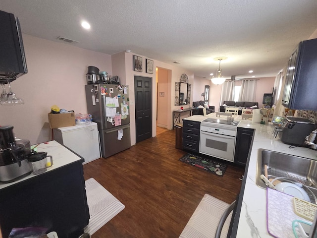 kitchen with a peninsula, oven, visible vents, freestanding refrigerator, and light countertops