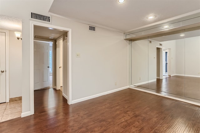 spare room with ornamental molding, wood finished floors, and visible vents