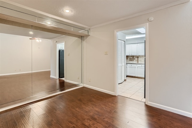 interior space with crown molding, baseboards, freestanding refrigerator, wood-type flooring, and recessed lighting