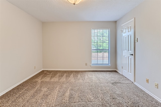 spare room with baseboards, carpet flooring, and a textured ceiling