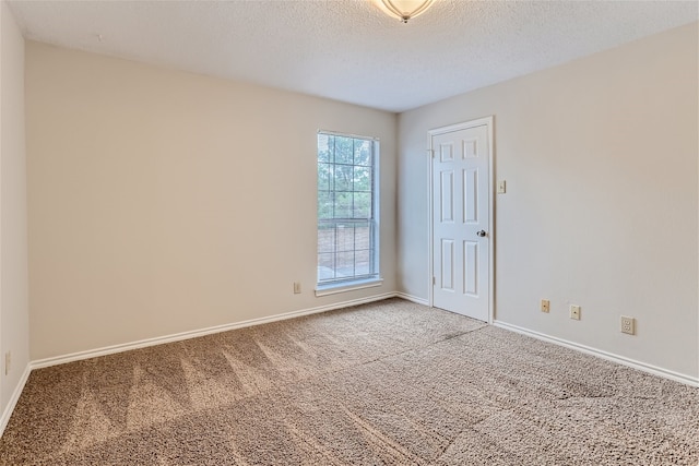 spare room with baseboards, a textured ceiling, and light colored carpet