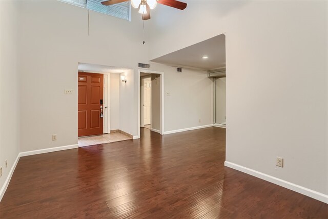unfurnished living room featuring ceiling fan, visible vents, baseboards, and a towering ceiling