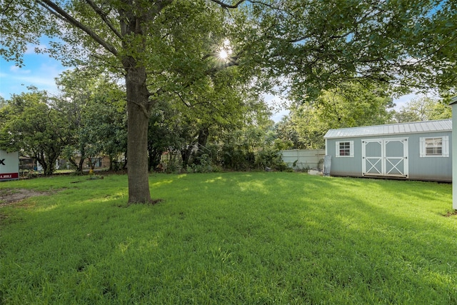 view of yard featuring an outbuilding, a storage unit, and fence
