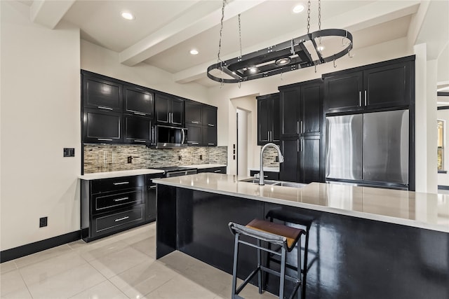 kitchen with stainless steel appliances, a sink, decorative backsplash, dark cabinets, and light countertops