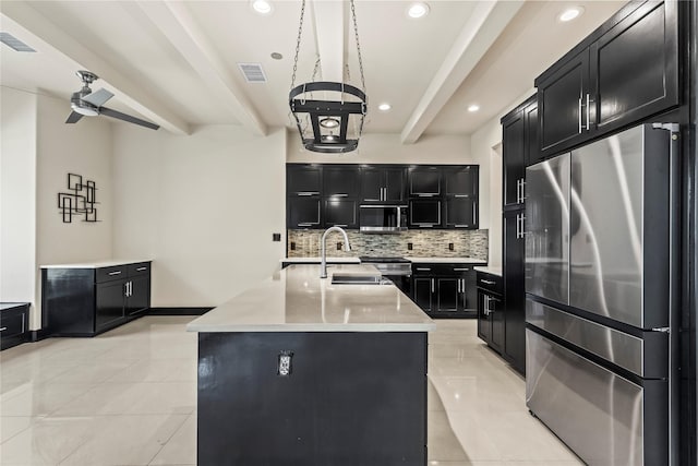 kitchen with a sink, tasteful backsplash, light tile patterned flooring, dark cabinetry, and appliances with stainless steel finishes