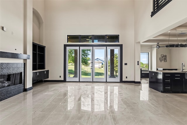 unfurnished living room with a fireplace, a high ceiling, marble finish floor, and baseboards