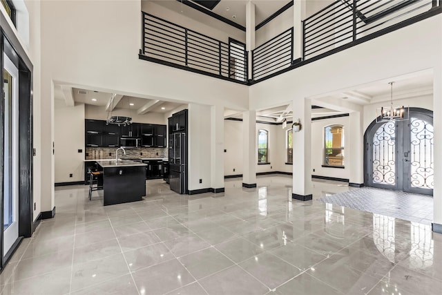 entrance foyer with a chandelier, baseboards, french doors, and a towering ceiling
