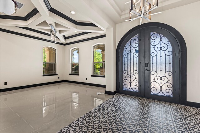 tiled entrance foyer featuring coffered ceiling, a notable chandelier, french doors, and baseboards