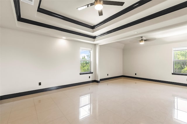 spare room featuring a ceiling fan, crown molding, light tile patterned flooring, a tray ceiling, and baseboards