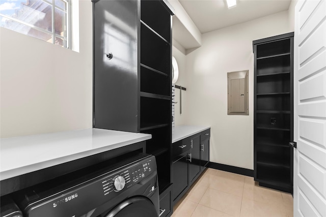 washroom featuring cabinet space, electric panel, light tile patterned floors, and washer / clothes dryer