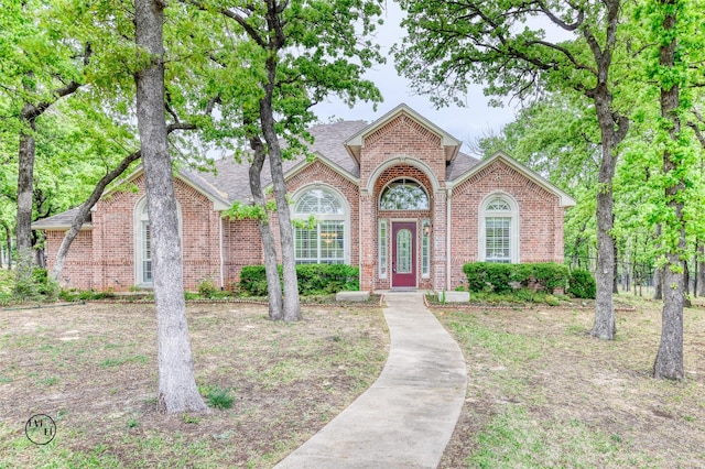 view of front of home with fence, brick siding, and roof with shingles