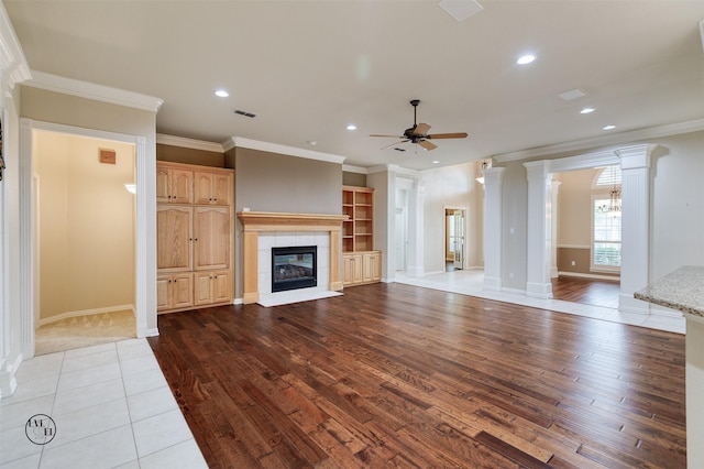 unfurnished living room with visible vents, a ceiling fan, crown molding, a fireplace, and hardwood / wood-style flooring