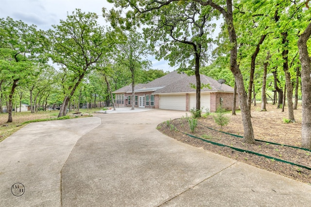 ranch-style home with an attached garage, a shingled roof, brick siding, and concrete driveway