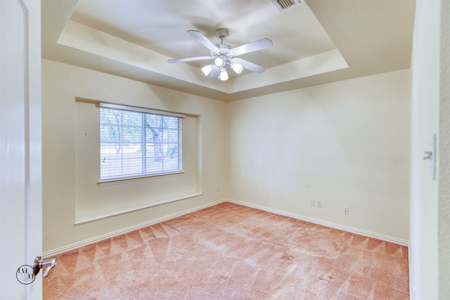 carpeted spare room featuring a ceiling fan, baseboards, and a raised ceiling