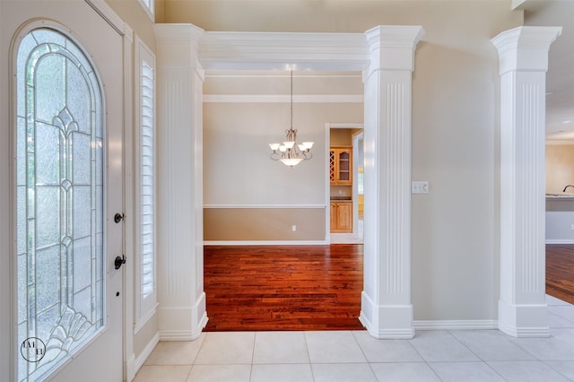 foyer entrance featuring a chandelier, wood finished floors, baseboards, and ornate columns