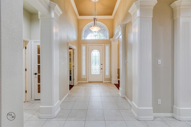 entryway featuring light tile patterned floors, crown molding, a towering ceiling, and decorative columns