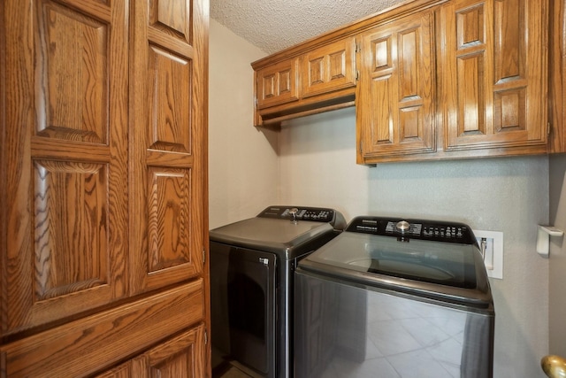 washroom with cabinet space, independent washer and dryer, and a textured ceiling