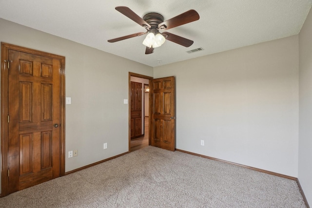 carpeted spare room with baseboards, a ceiling fan, and visible vents