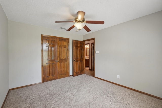 unfurnished bedroom featuring visible vents, baseboards, carpet, a closet, and ceiling fan