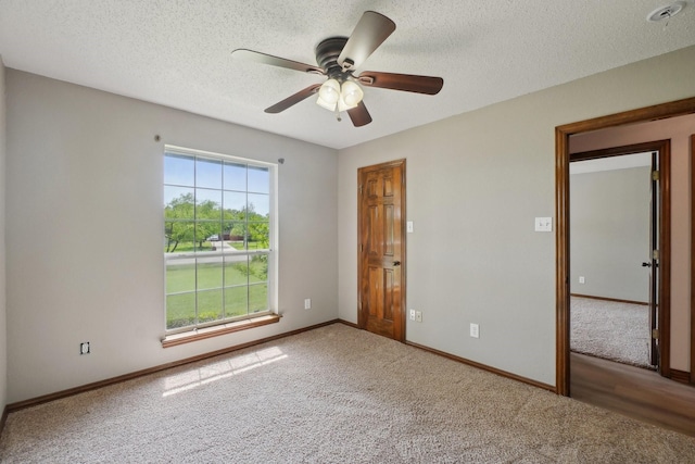 unfurnished room featuring ceiling fan, baseboards, a textured ceiling, and carpet