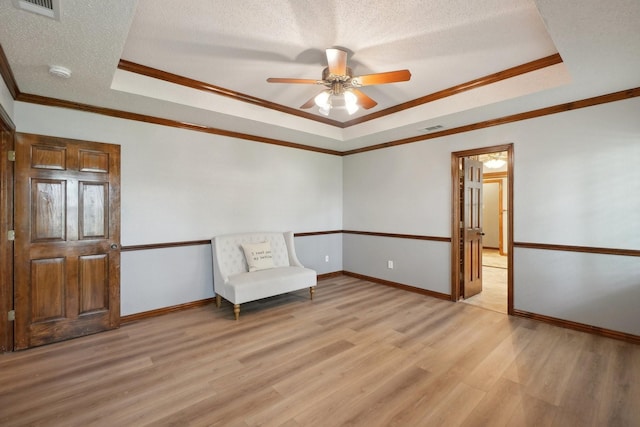 unfurnished room with a tray ceiling, visible vents, and light wood finished floors