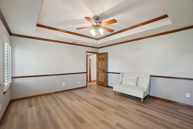 unfurnished room with a raised ceiling, visible vents, light wood-style floors, a ceiling fan, and ornamental molding