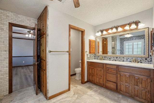 full bathroom featuring a ceiling fan, a sink, a textured ceiling, and toilet