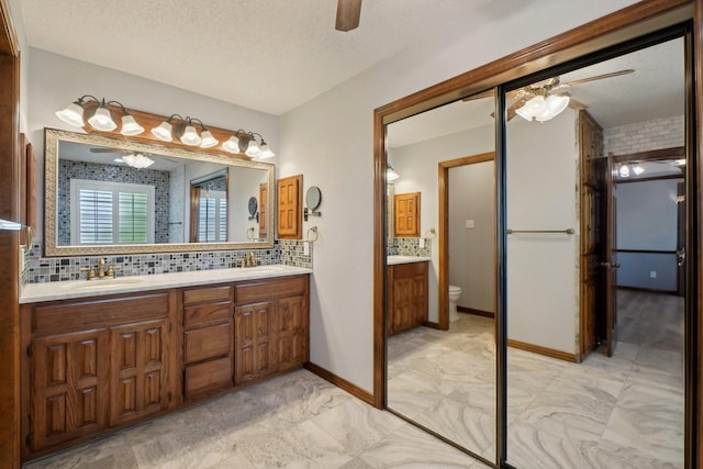 full bathroom with a ceiling fan, a sink, decorative backsplash, double vanity, and toilet