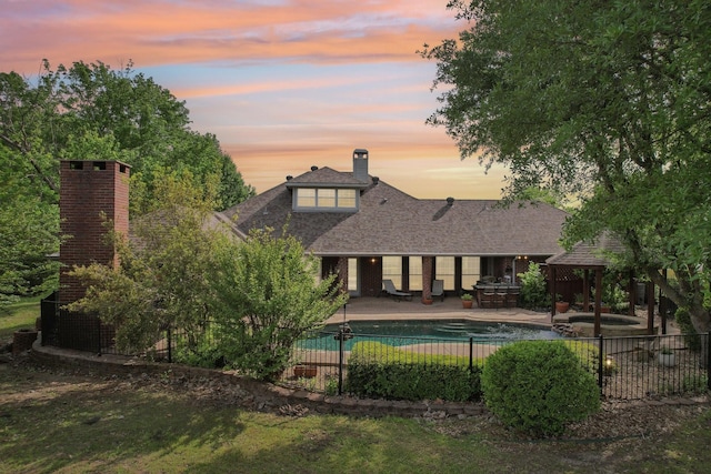 pool at dusk featuring a gazebo, a patio area, a pool with connected hot tub, and fence