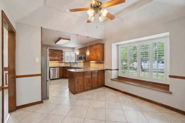 kitchen featuring a peninsula, a sink, decorative backsplash, brown cabinets, and appliances with stainless steel finishes