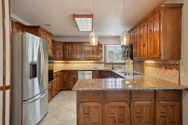 kitchen with stainless steel appliances, a peninsula, a sink, visible vents, and brown cabinetry