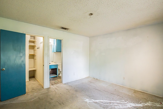 unfurnished bedroom with carpet flooring, a textured ceiling, visible vents, a spacious closet, and a closet