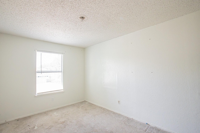 empty room with a textured ceiling and light colored carpet