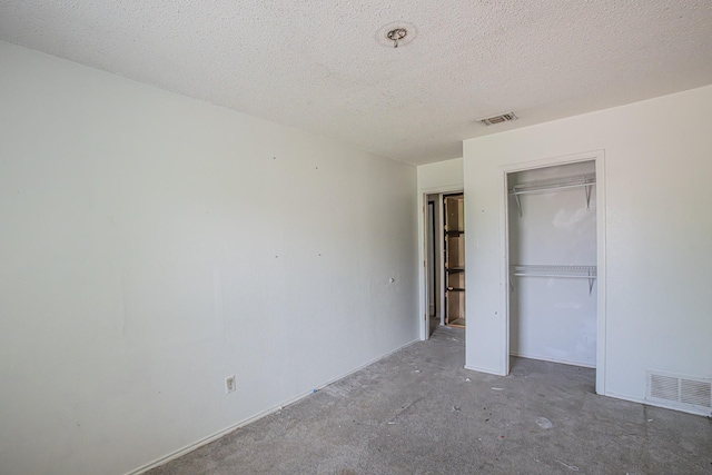unfurnished bedroom with a textured ceiling, visible vents, and a closet