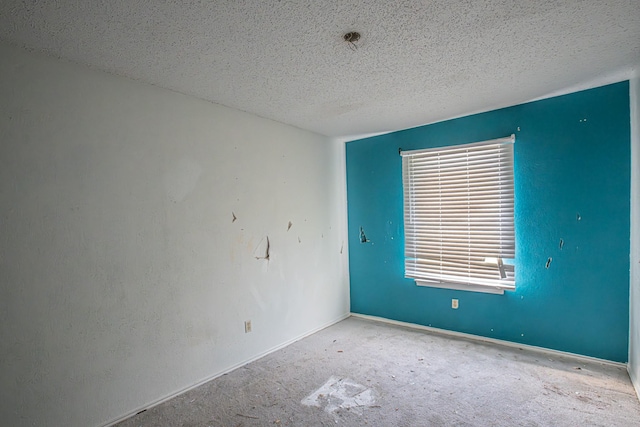 carpeted spare room with a textured ceiling and baseboards