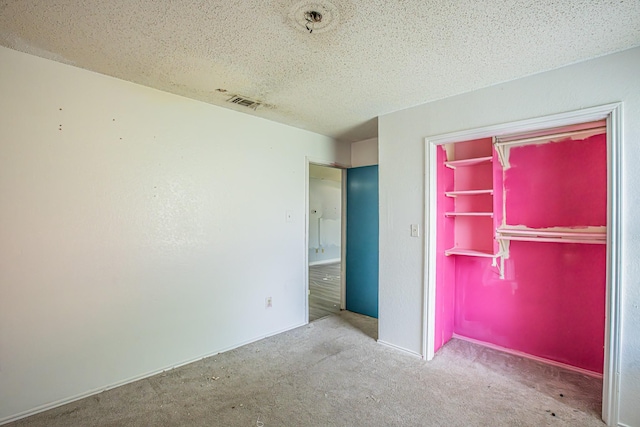 unfurnished bedroom with a textured ceiling, carpet floors, a closet, and visible vents