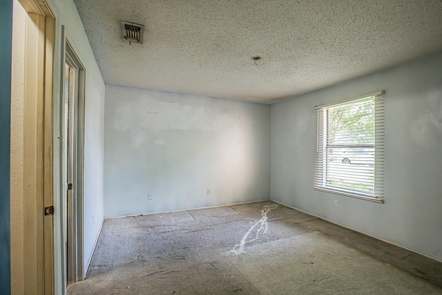 unfurnished room featuring carpet floors, a textured ceiling, and visible vents