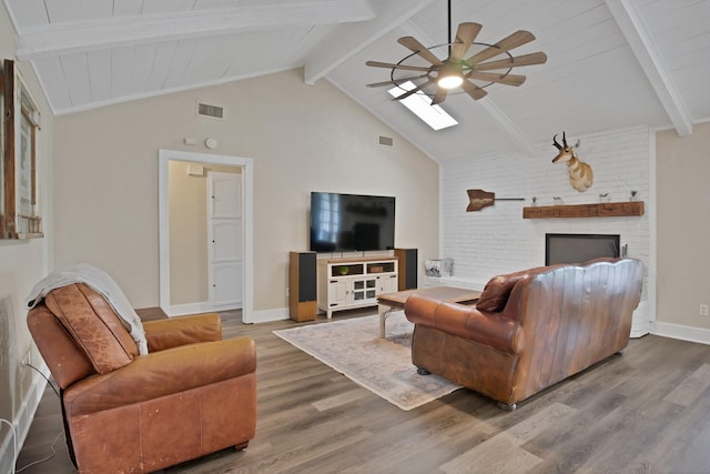 living room featuring ceiling fan, lofted ceiling with skylight, wood finished floors, and visible vents