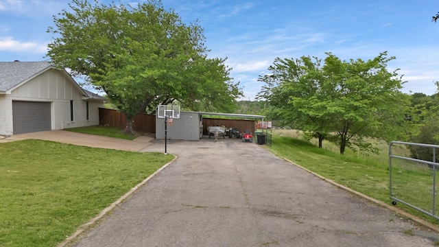 exterior space with a lawn, driveway, fence, and a carport