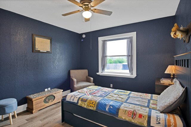 bedroom with ceiling fan, baseboards, a textured wall, and wood finished floors